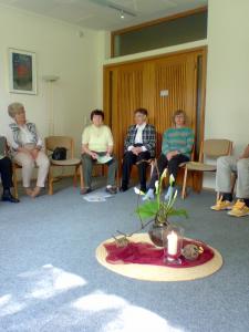 Gruppe im Stuhlkreis um eine Kerze und eine Pflanze
