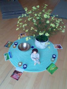 Bodenmandala mit gelb blühendem Strauch, Klangschale und Bildkarten