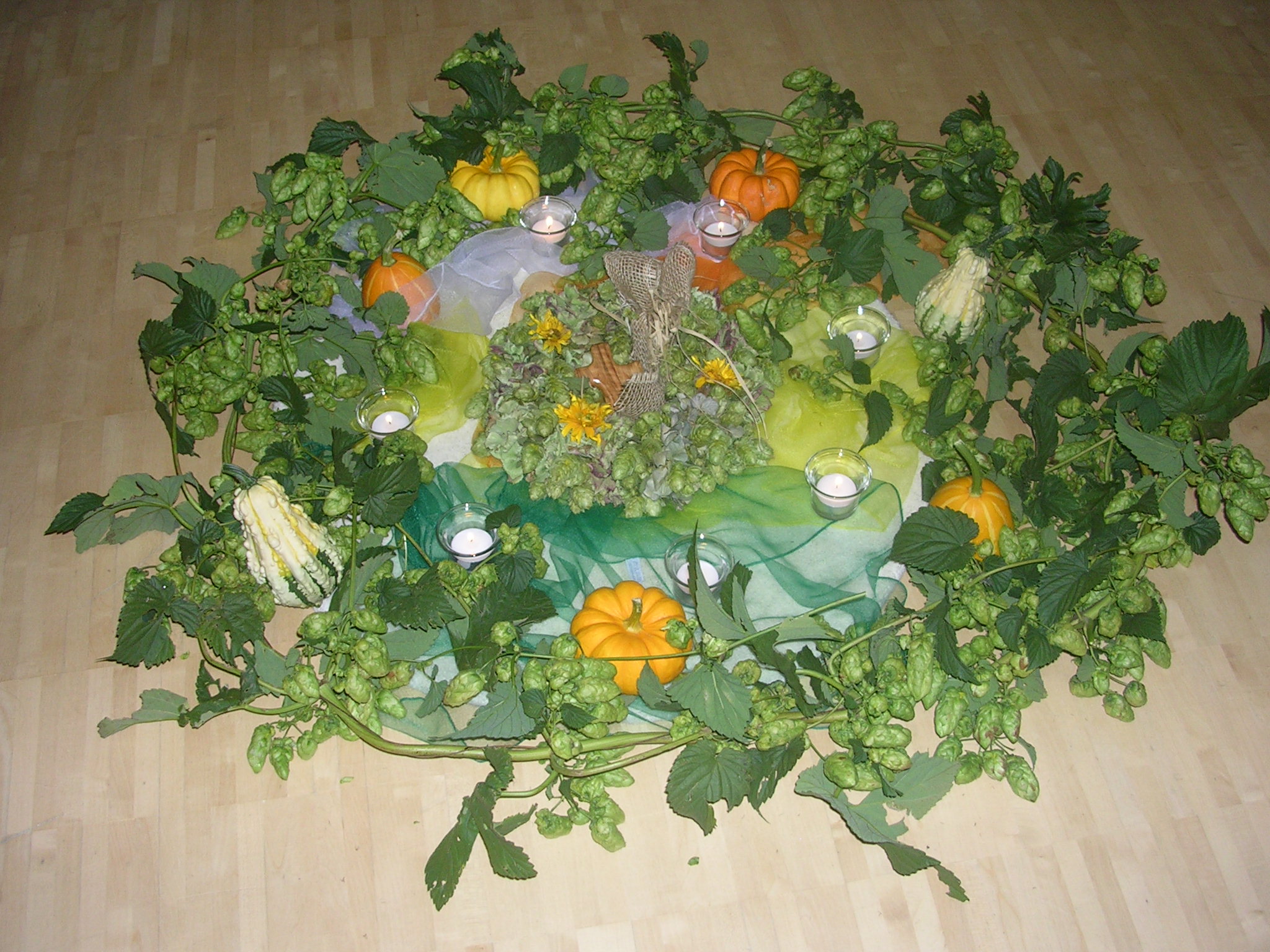 Herbstliches Bodenmandala aus Hopfenranken, Zierkürbissen und Teelichtern