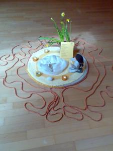Mandala mit Narzissen und einem roten Faden, der sich über den Boden zieht